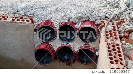 Red utility pipes emerging from the ground at a construction site showing preparation for drainage and plumbing installation Red utility pipes emerging from the ground at a construction site showing preparation for drainage and plumbing installation 119960547