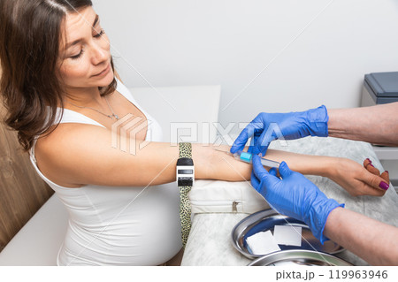 Nurse takes a blood sample from arm of pregnant woman 119963946
