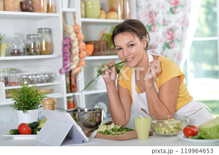 Portrait of a beautiful young woman cooking in the kitchen Portrait of a beautiful young woman cooking in the kitchen 119964653