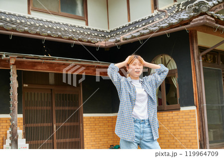 古民家の前で頭を抱える女性　空き家　田舎　相続 119964709