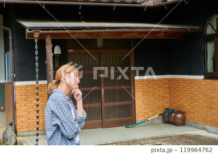 古民家の前で首をかしげる女性　空き家　相続　田舎 119964762