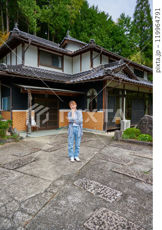 古民家の前で首をかしげる女性　空き家　相続　田舎 119964791