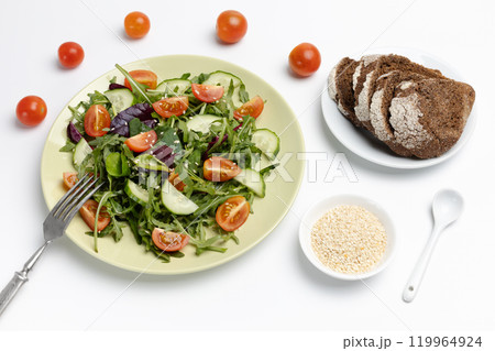 Vegetable salad of tomato, cucumber, greens on the plate with a fork. 119964924