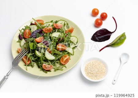 Vegetable salad of tomato, cucumber, greens on the plate with a fork. 119964925