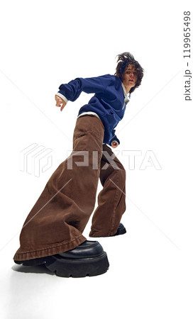 Fashion-forward woman dressed in navy pullover and wide-legged brown trousers, captured from low angle, creating powerful and grounded presence. Fashion-forward woman dressed in navy pullover and wide-legged brown trousers, captured from low angle, creating powerful and grounded presence. 119965498