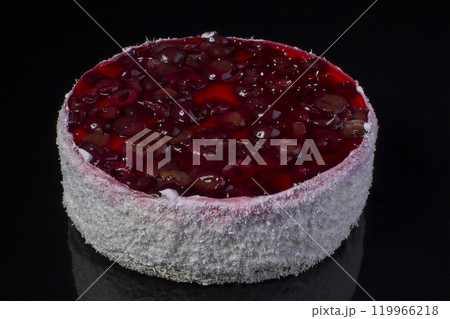 Big cake in coconut shavings with a cherry in jelly on a black background 119966218