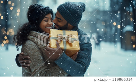 joyful couple embraces in snowy setting, sharing gift. 119966314