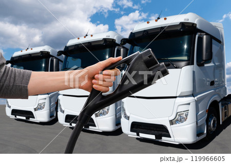 Hand with charging plug on a background of electric truck. Concept. Hand with charging plug on a background of electric truck. Concept. 119966605