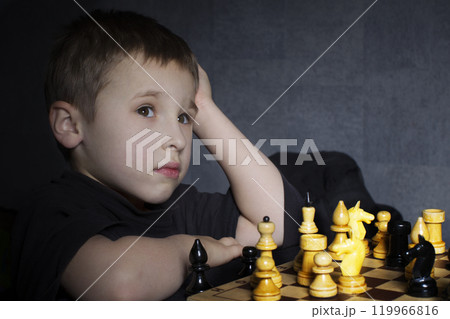 A preschool child plays chess. The little boy is thinking over the move. The course of the horse. A preschool child plays chess. The little boy is thinking over the move. The course of the horse. 119966816