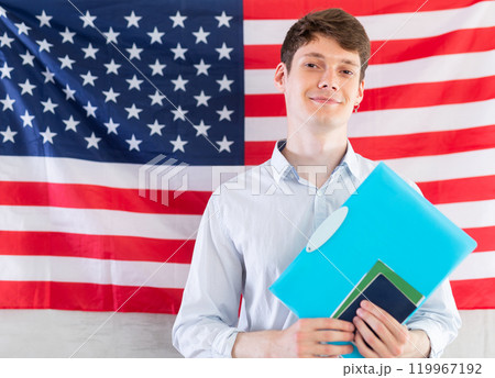 Young guy with documents posing against background of USA flag Young guy with documents posing against background of USA flag 119967192