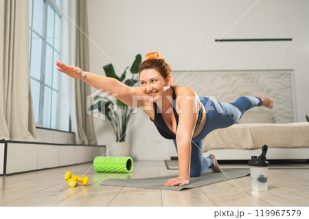 Yoga fitness workout training. Woman practicing yoga at home. Plus size female doing sports exercise on yoga mat indoor. Girl in sportswear have training workout for weight loss. Sport and fitness Yoga fitness workout training. Woman practicing yoga at home. Plus size female doing sports exercise on yoga mat indoor. Girl in sportswear have training workout for weight loss. Sport and fitness 119967579