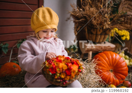 A child in a yellow beret gathers colorful flowers in a cozy autumn setting with pumpkins A child in a yellow beret gathers colorful flowers in a cozy autumn setting with pumpkins 119968192