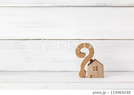 Wooden Question Mark and Mini House on White Wooden Background Symbolizing Real Estate Uncertainty 119969298