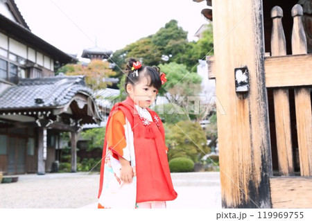 七五三詣で可愛い三歳の女の子、神社仏閣での和装ロケーション撮影、被布キッズフォト家族写真 119969755
