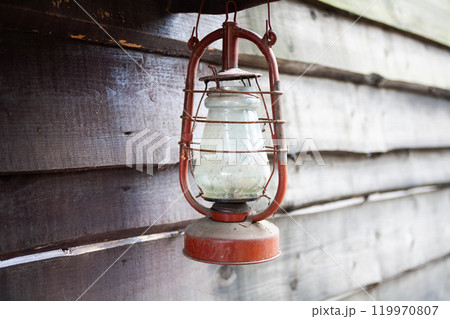 Antique rusty kerosene lantern on wooden wall. 119970807