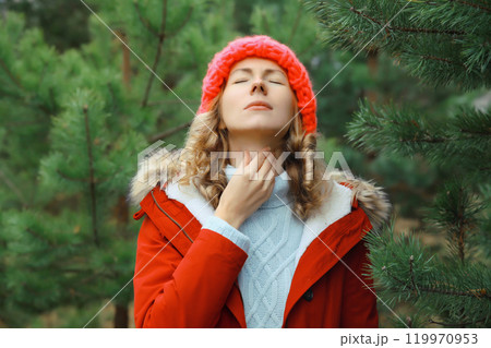 Sick exhausted woman suffering from acute sore in throat flu, touches neck with hand outdoor in park 119970953