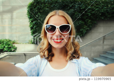 Happy cheerful smiling young woman taking selfie with phone, joyful girl using smartphone in city 119970965