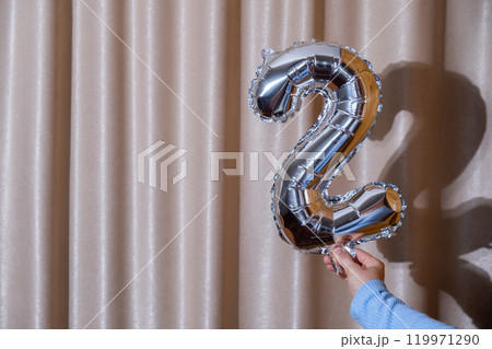 2 two metallic balloon isolated on Altas textile background. Greeting card silver foil balloon number Happy birthday holiday concept. Copy space for text. Celebration party congratulation 119971290