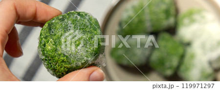 Unrecognizable woman showing into camera frozen food spinach cubes homemade. Harvesting concept. Stocking up vegetables for winter storage 119971297