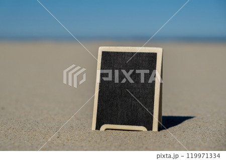 Empty blackboard frame board with copy space for your text or design displays on sandy beach. Summer vacation and holiday business travel concept. Template Mock up for sale promotion advertisement 119971334