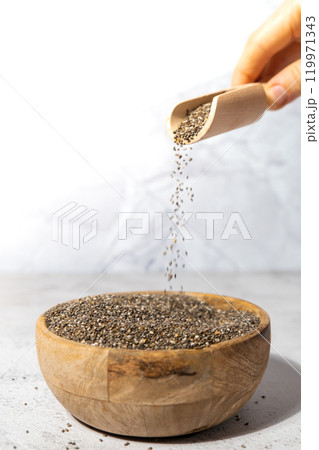 Chia seeds fall in wooden bowl. Healthy superfood rich in Omega 3 fatty acids. Dry healthy natural ingredient. Chia grains are falling Chia seeds fall in wooden bowl. Healthy superfood rich in Omega 3 fatty acids. Dry healthy natural ingredient. Chia grains are falling 119971343