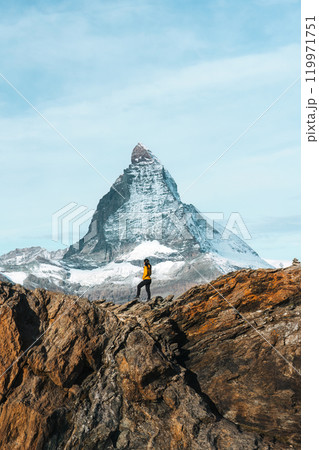 A woman standing on top of rocky mountain with Matterhorn mountain on sunny day at Switzerland A woman standing on top of rocky mountain with Matterhorn mountain on sunny day at Switzerland 119971751