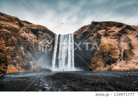 Powerful Skogafoss waterfall flowing from volcanic mountain in autumn at Iceland 119971777