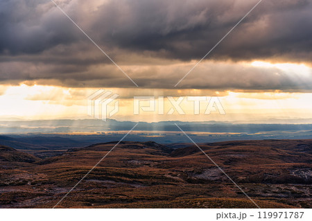 Sunbeam shining through cloudy over autumn wilderness 119971787
