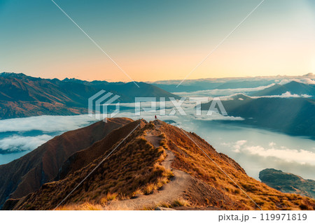 Female tourist hiking on Roys Peak summit mountain with foggy in the morning at New Zealand Female tourist hiking on Roys Peak summit mountain with foggy in the morning at New Zealand 119971819