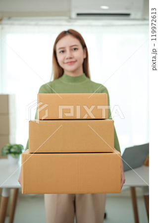 A woman is holding three boxes in her hands 119972613