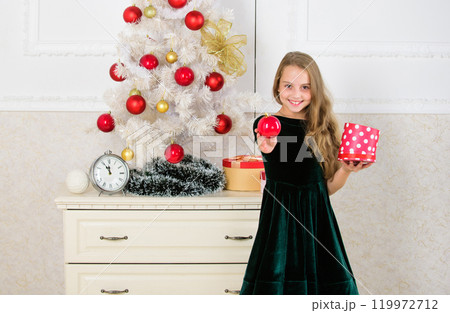 Traditional family holiday. Kid girl near christmas tree hold gift box. Child celebrate christmas at home. Favorite day of the year. Time to open christmas gifts. Opening christmas presents 119972712