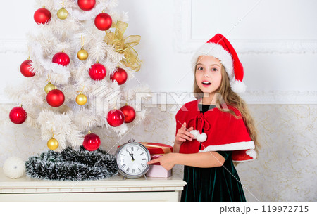 Girl kid santa hat costume with clock counting time to new year. How much time before. Last minute till midnight. New year countdown. Last minute new years eve plans that are actually lot of fun 119972715