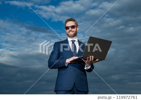 Professional man using laptop. Professional businessman in suit. Successful ceo smiling in professional wear Professional man using laptop. Professional businessman in suit. Successful ceo smiling in professional wear 119972761