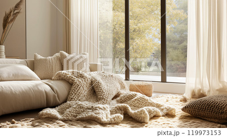 A cozy corner with a plush sofa chunky knit pillows and dried flowers in a sunlit room in soft beige colors. Private personal relaxation home area concept 119973153