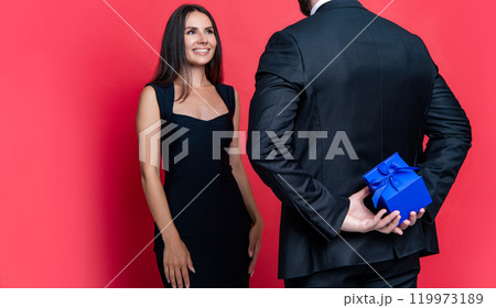 Couple in love isolated on red. Romantic proposal with gift. Present. Grand proposal. Man making proposal to woman. Man give present gift box for Valentines day to woman. Happy Valentines day 119973189