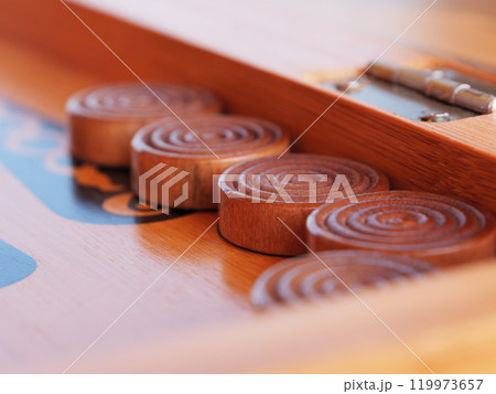 Wooden game pieces arranged neatly on a traditional backgammon game board 119973657