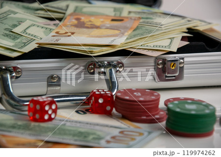 A silver case filled with cash, dice, and poker chips A silver case filled with cash, dice, and poker chips 119974262