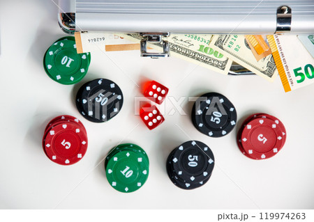 A close-up shot of a table with poker chips, dice, and a silver case full of cash A close-up shot of a table with poker chips, dice, and a silver case full of cash 119974263