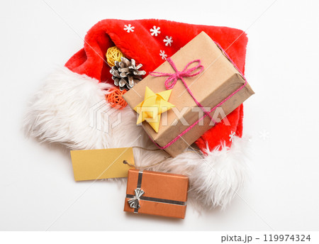 Santa red hat white background top view. Santa hat with christmas gift box. Keep family traditions. Christmas presents from santa. Attributes of winter holidays. New year and christmas celebration 119974324