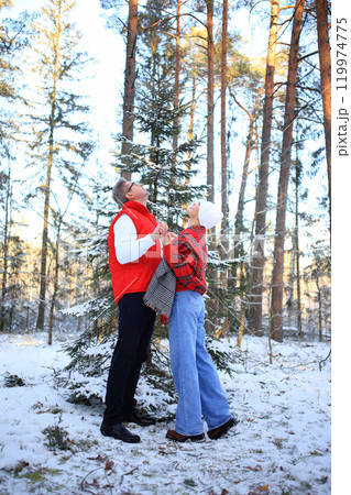 a couple holding hands in a picturesque, snow-covered forest, gazing upward towards the sky.Love in the Snow a couple holding hands in a picturesque, snow-covered forest, gazing upward towards the sky.Love in the Snow 119974775
