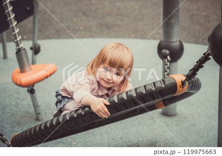 cute little girl on a swing on playground cute little girl on a swing on playground 119975663