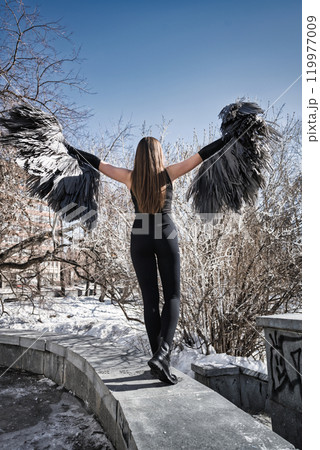 a girl in a black suit and angel wings on the background of the rotunda and the sky. 119977009