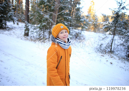 A young man walks leisurely through a picturesque snowy forest, surrounded by towering trees blanketed in fresh snow. A young man walks leisurely through a picturesque snowy forest, surrounded by towering trees blanketed in fresh snow. 119978236