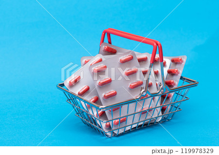 Pills and Capsules in Shopping Basket on Blue Background Pills and Capsules in Shopping Basket on Blue Background 119978329