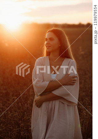 A woman is standing in a field of tall grass A woman is standing in a field of tall grass 119979554