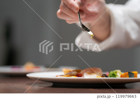 料理の盛り付けをする男性シェフの手元 119979663