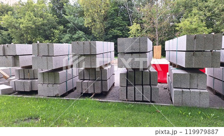 Stacks of construction concrete blocks on grass with forest background Stacks of construction concrete blocks on grass with forest background 119979887
