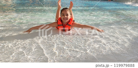 Joyful child floating in pool with bright orange life vest Joyful child floating in pool with bright orange life vest 119979888
