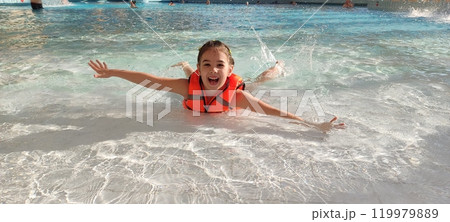 Joyful child swimming in a pool with a bright orange life vest Joyful child swimming in a pool with a bright orange life vest 119979889
