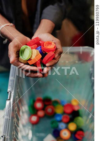 Hands holding red plastic bottle caps 119980769